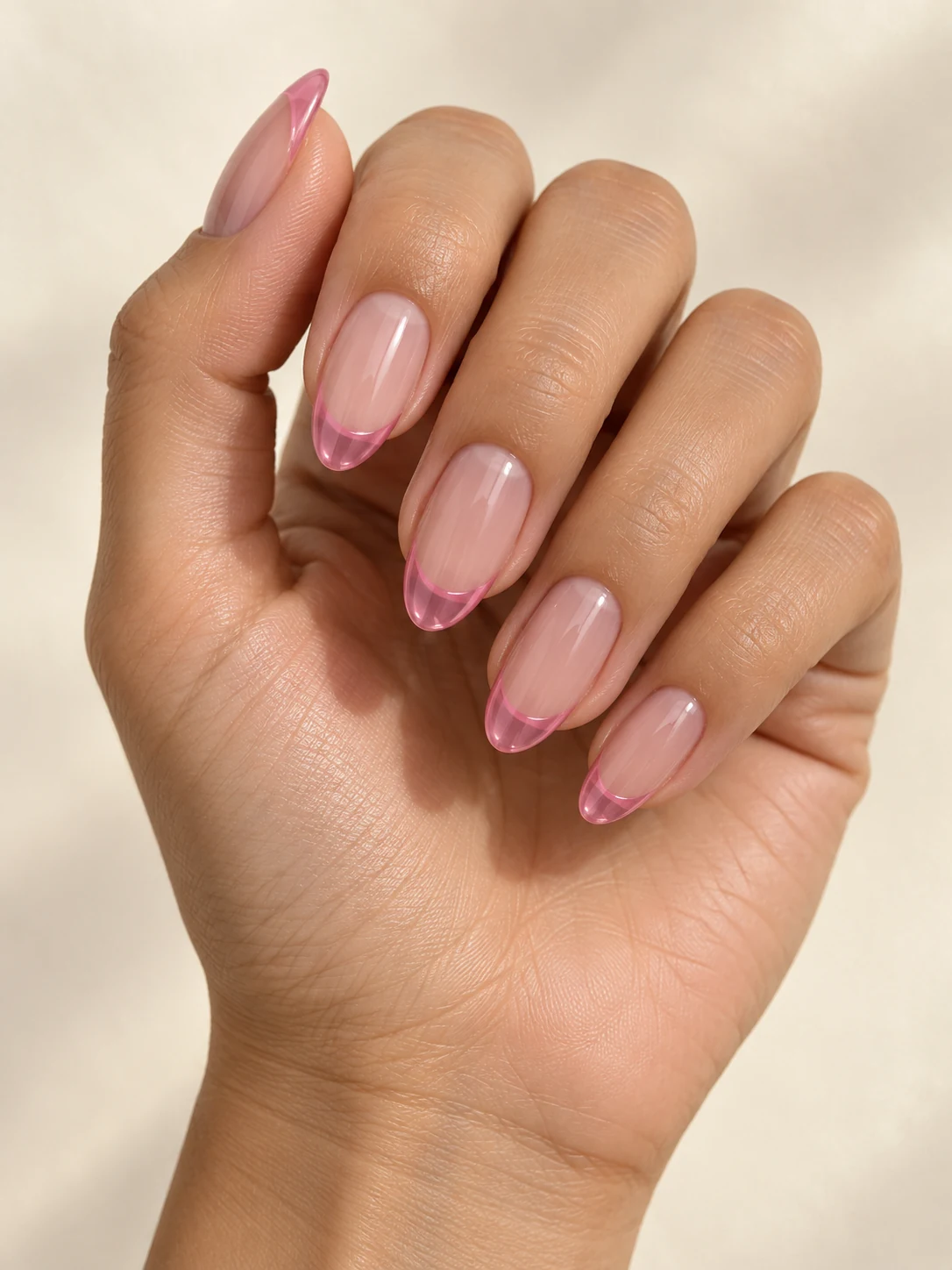 Translucent nude almond nails with clear candy-pink glass-like French tips, subtle visible transparency on warm medium skin; medium almond manicure.