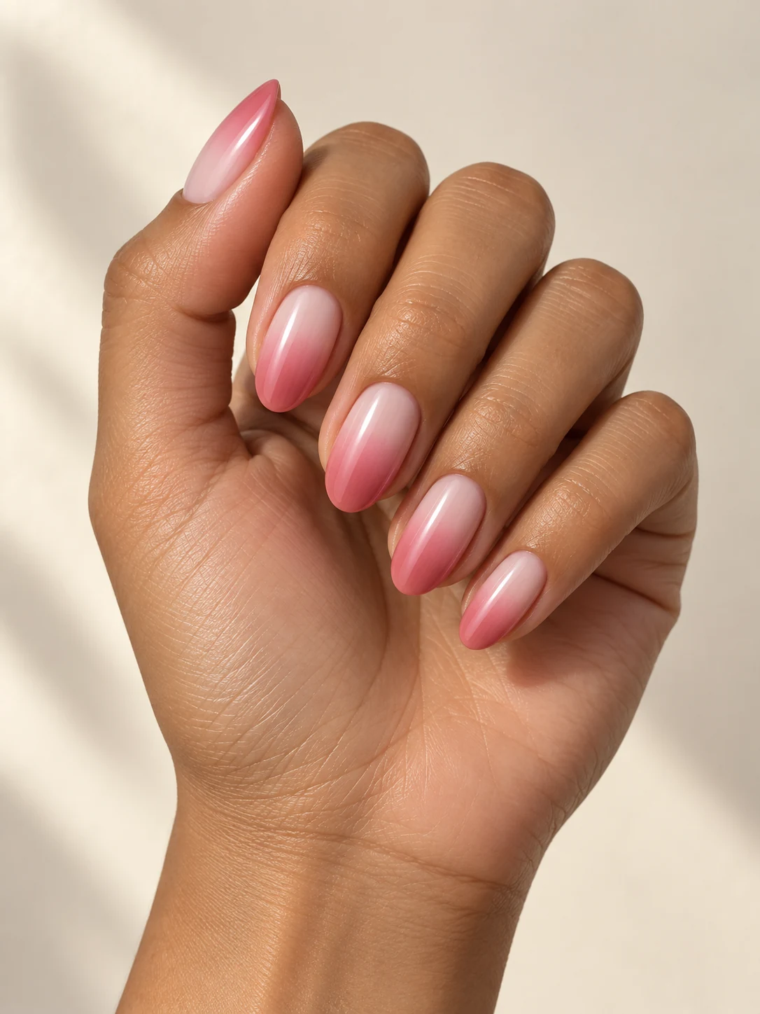 A soft gradient from milky white cuticles into deeper rose-pink free edges, smooth transition and delicate gloss on olive tan skin; medium oval manicure.