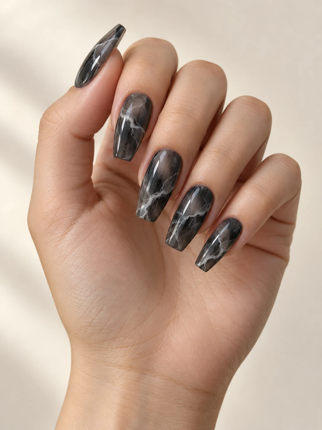 Smoky translucent grey-black nails with wispy white marble veins, cool dark stone-inspired depth on fair neutral skin; medium coffin manicure.